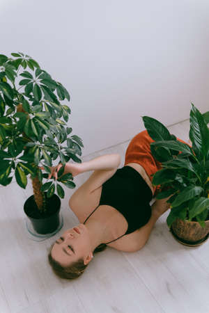 Portrait of young caucasian woman in red cloth laying near flowerpotの写真素材