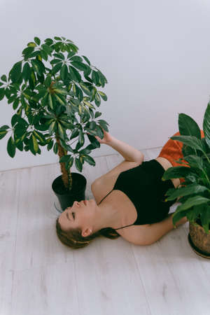 Portrait of young caucasian woman in red cloth laying near flowerpotの写真素材