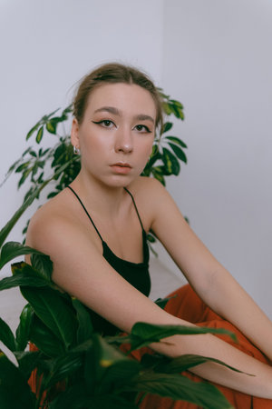 Portrait of young caucasian woman in red cloth sitting near flowerpot