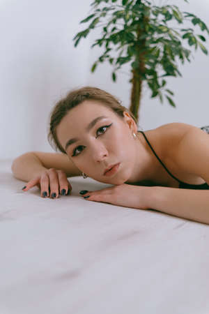 Portrait of young caucasian woman in red cloth laying near flowerpotの写真素材