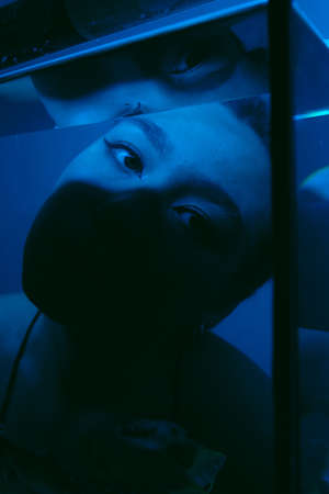 porrait of woman underwater with fish concept blue lightの写真素材