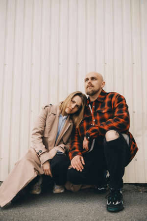Loving couple stand near wall and look in cameraの写真素材
