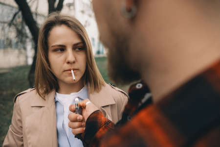 Man lighting womans cigarette at streetの写真素材