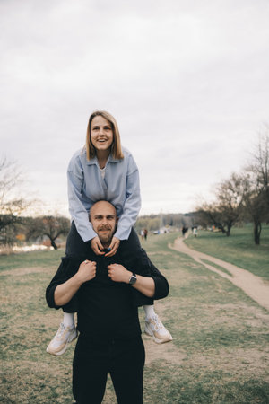 man carries a woman in his arms in the park and they have fun and happyの写真素材