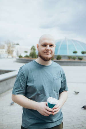 Bald bearded man drinking coffee outdoors and smilingの写真素材