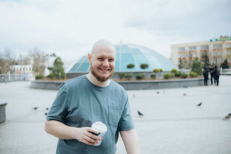 Bald bearded man drinking coffee outdoors and smilingの写真素材