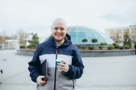 Bald bearded man drinking coffee outdoors and smilingの写真素材