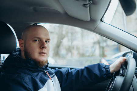 Handsome elegant bearded bald head serious man drives a car
