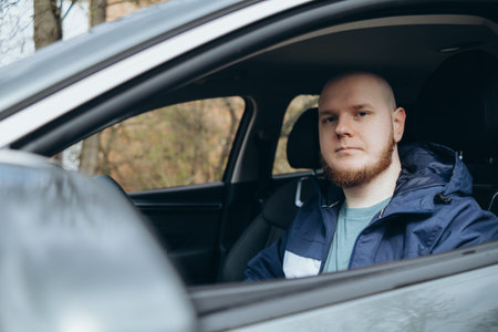 Handsome elegant bearded bald head serious man drives a car