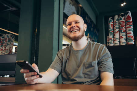 Smartphone man sms texting drinking at cafe summer. Happy casual urban bald bearded manの写真素材