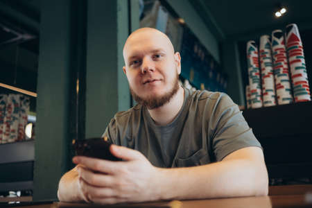 Smartphone man sms texting drinking at cafe summer. Happy casual urban bald bearded manの写真素材