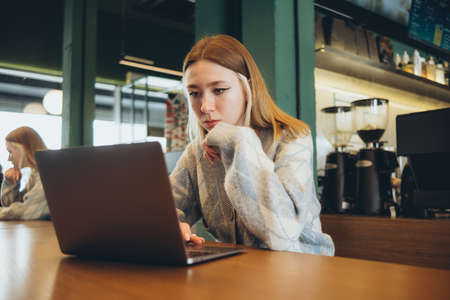 Girl working at her laptop sitting in the cafe happyの写真素材