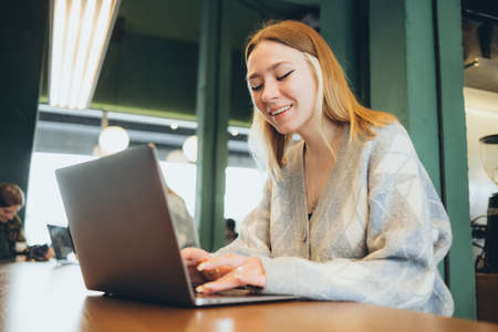 Girl working at her laptop sitting in the cafe happyの写真素材