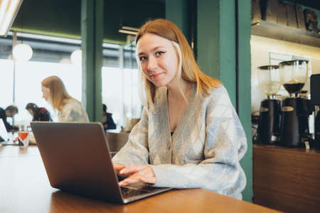 Girl working at her laptop sitting in the cafe happyの写真素材