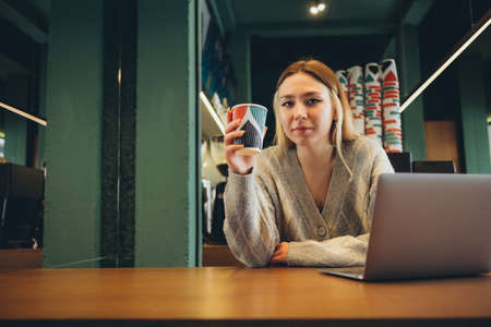 Girl working at her laptop sitting in the cafe happyの写真素材