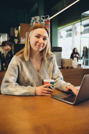 Girl working at her laptop sitting in the cafe happyの写真素材