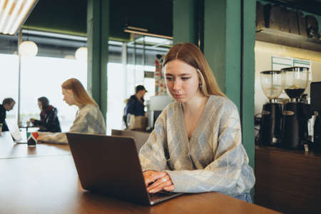 Girl working at her laptop sitting in the cafe happyの写真素材