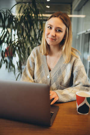 Girl working at her laptop sitting in the cafe happyの写真素材