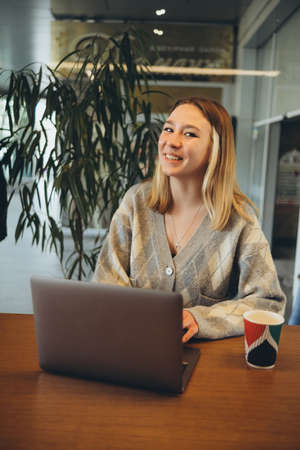 Girl working at her laptop sitting in the cafe happyの写真素材