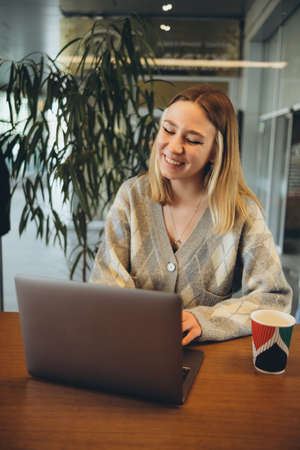 Girl working at her laptop sitting in the cafe happyの写真素材