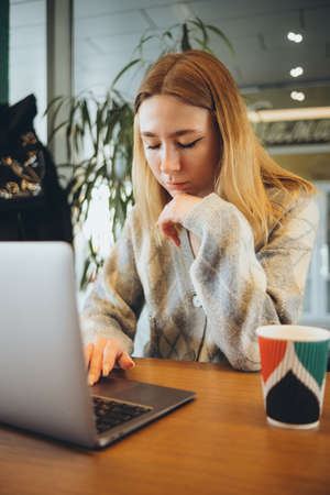 Girl working at her laptop sitting in the cafe happyの写真素材