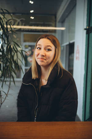 Young smiling attractive lady drinking coffee while ralxing in cafe indoorsの写真素材