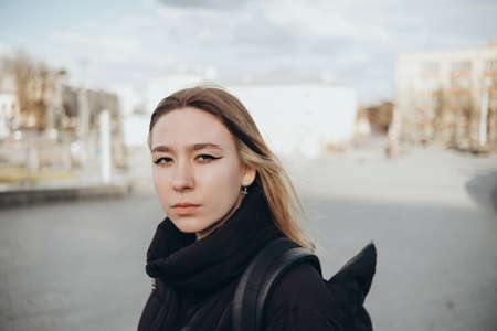 Sunny lifestyle fashion portrait of young stylish hipster woman walking on the street, travel with backpack.の写真素材