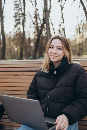 Smiling woman studying on laptop at park happyの写真素材