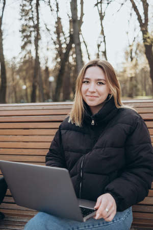 Smiling woman studying on laptop at park happyの写真素材