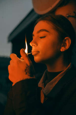portrait of a woman in red light with a burning match in her mouthの写真素材