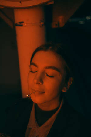 portrait of a woman in red light with a burning match in her mouthの写真素材