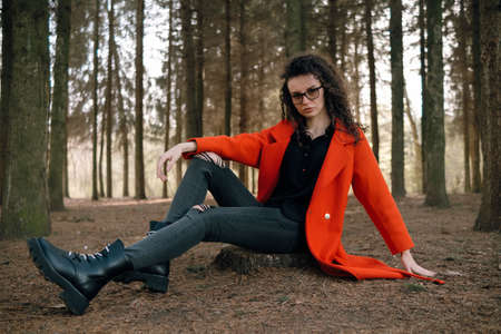 portrait of curly brunette woman in red coat in the parkの写真素材