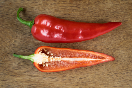 Sliced red sweet bulgarian pepper isolated on wooden backgroundの写真素材