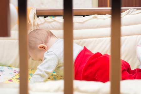 Cute baby lying on his stomach in his bed.の写真素材