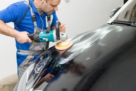Man on a car wash polishing car with a polish machineの写真素材