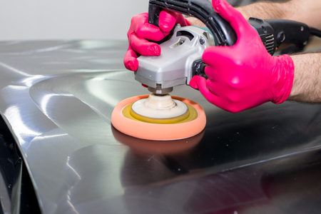 A man polishes a black car with a polishing machineの写真素材