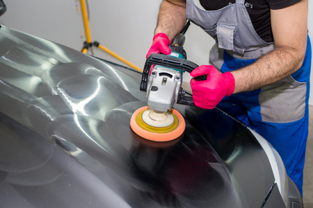A man polishes a black car with a polishing machineの写真素材
