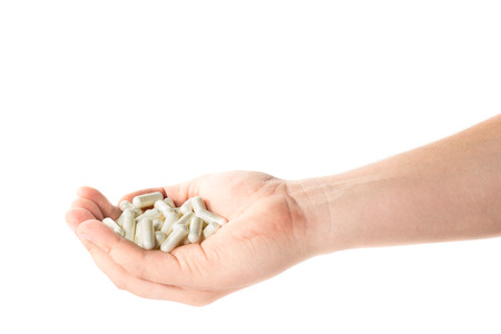 Image of a hand full of medical capsules on a white backgroundの写真素材
