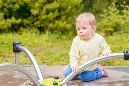 A baby boy rides on a carousel in the playgroundの写真素材