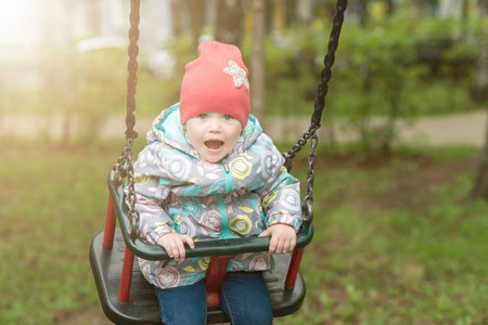 A small child is happily swinging on a swing