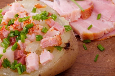 Baked Jacket Potato with Bacon, Paprika, Butter and Spring Onion closeup on wooden backgroundの写真素材