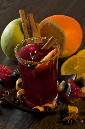 Arrangement of Fruits with Red Currant, Apple and Orange with Glass of Mulled Wine and Cinnamon Stick, Slice of Orange and Anise Star closeup on Dark Wood backgroundの写真素材