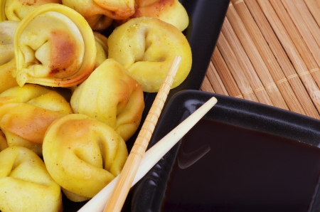Delicious Fried Crispy Dumplings with Soy Sauce and Chopsticks closeup on Straw mat backgroundの写真素材