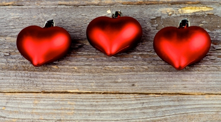 Three Red Plastic Hearts In a Row closeup on Rustic Wood surfaceの写真素材