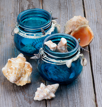 Collection of Sea Shells and Corals in Blue Glass Jars closeup on Rustic Wooden backgroundの写真素材