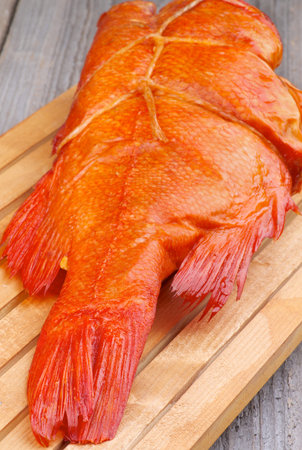 Delicious Smoked Red Snapper Fish Full Body on Cutting Board closeup on Wooden background
