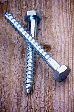 Big Stainless Steel Bolts isolated on Rustic Wooden backgroundの写真素材