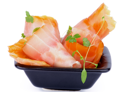 Snack of Swirled Slices of Delicious Smoked Sturgeon with Greens in Black Bowl isolated on white backgroundの写真素材