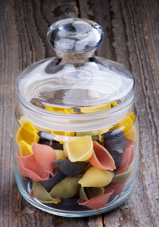 Colorful Conchiglie Pasta in Glass Jar isolated Wooden backgroundの写真素材