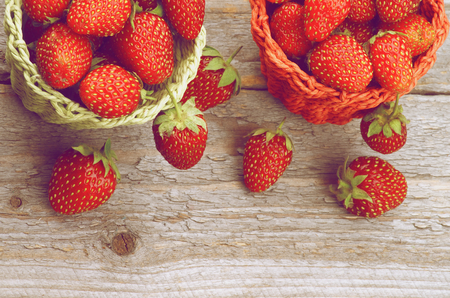 Forest Strawberries in Red and Green Wicker Baskets on Rustic Wooden background  Retro Styledの写真素材